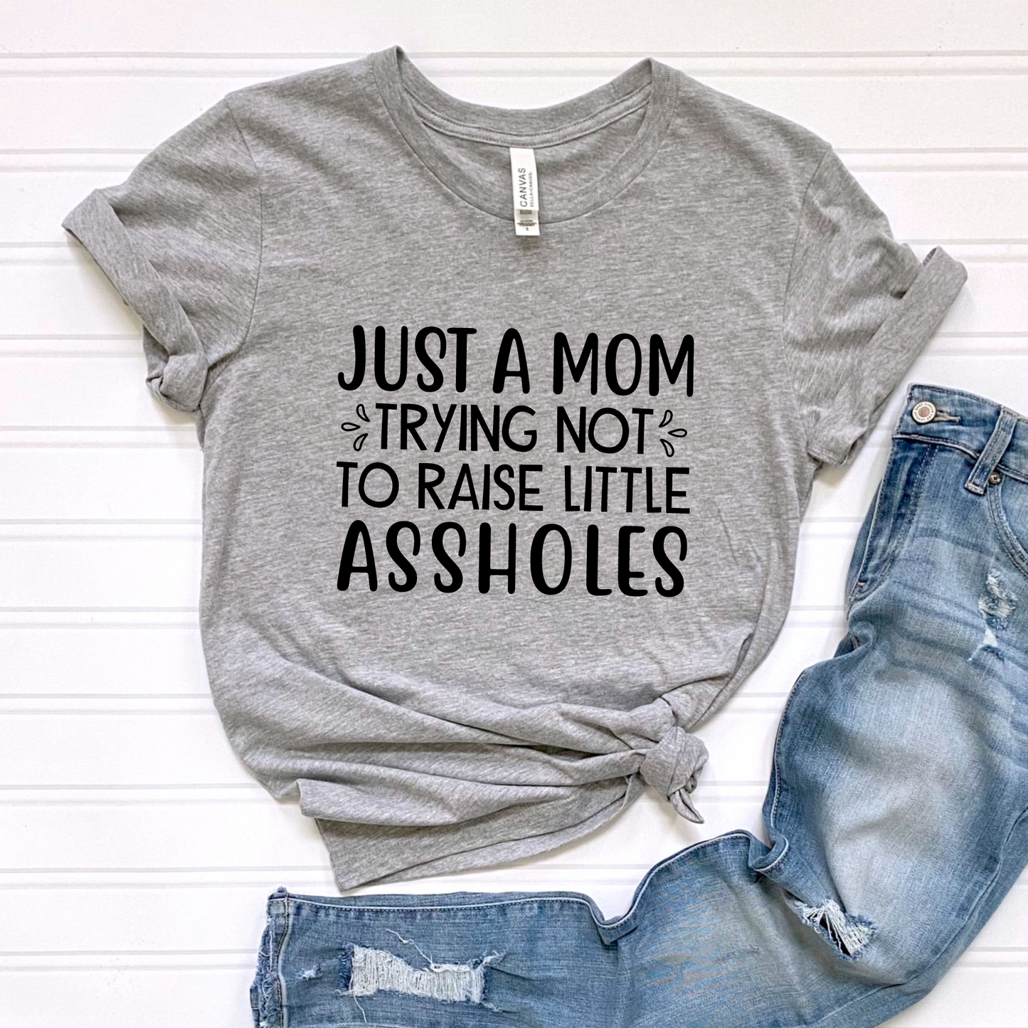 Just a mom trying not to raise little assholes Unisex Jersey Short Sleeve Tee