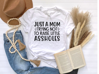 Just a mom trying not to raise little assholes Unisex Jersey Short Sleeve Tee